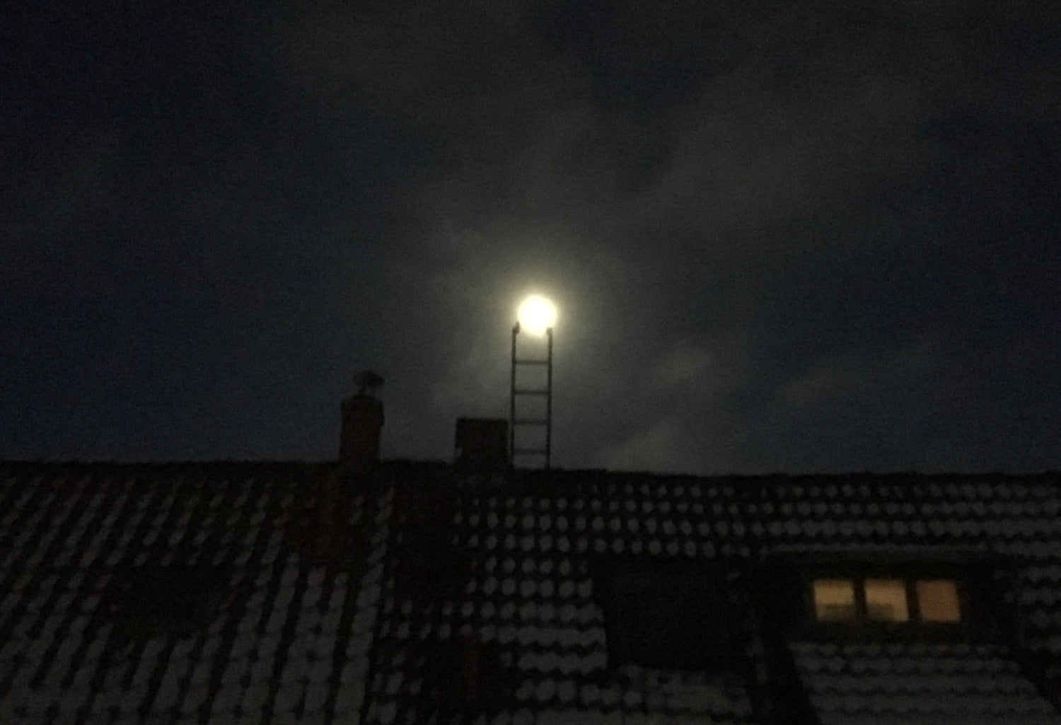 Die Leiter auf einem Hausdach stößt optisch an den Mond 